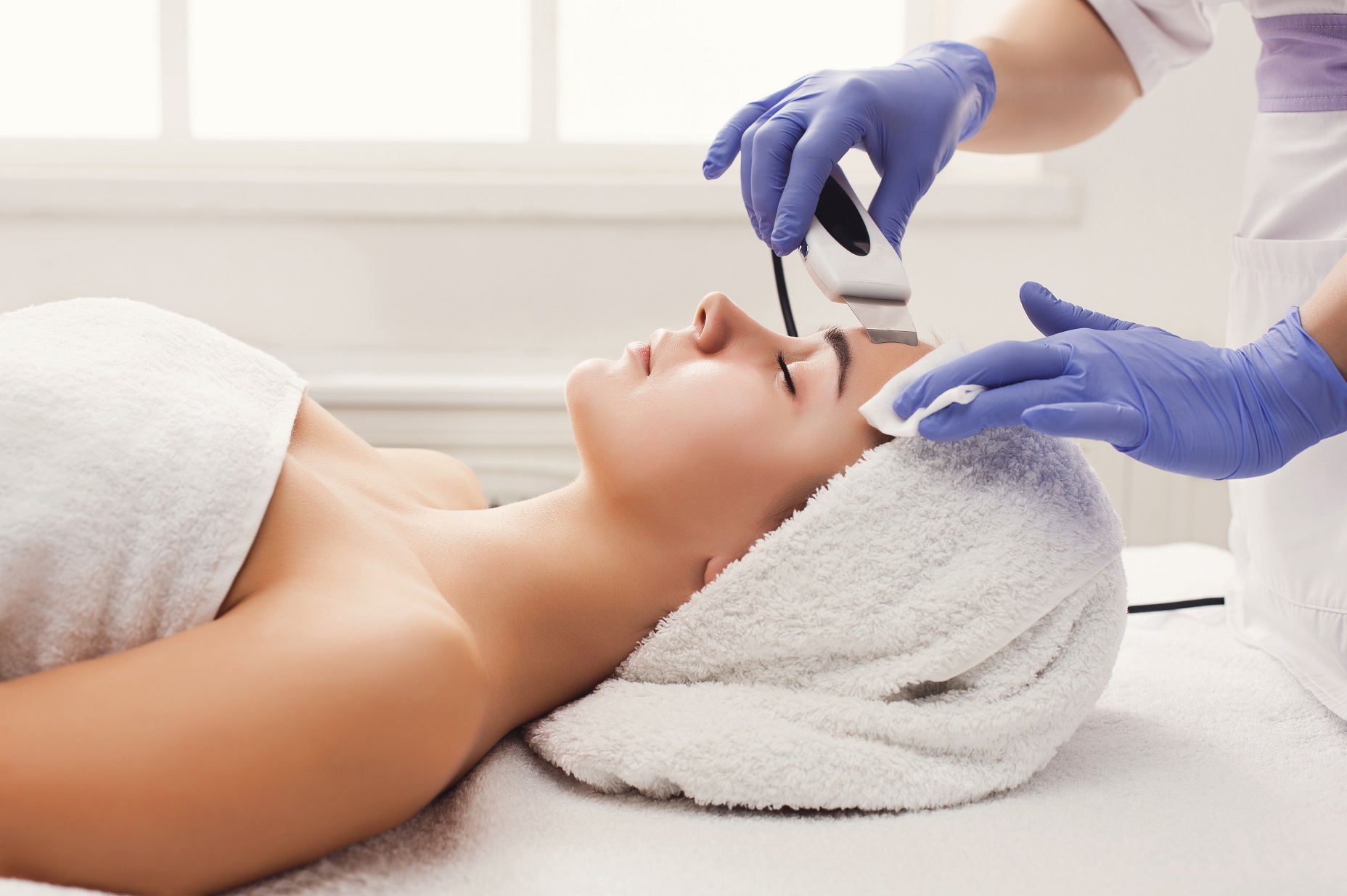 Rejuvenating facial treatment. Model getting lifting therapy massage in a beauty SPA salon. Exfoliation, stimulation and hydratation. Aesthetic cosmetology, closeup, copy space